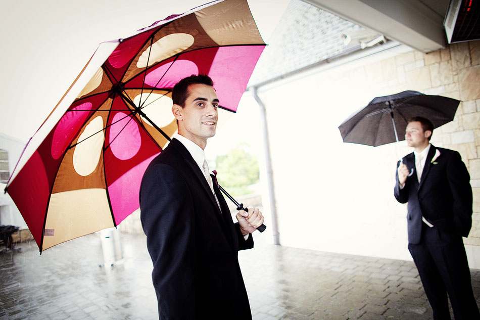 Ushers at wedding holding umbrellas.