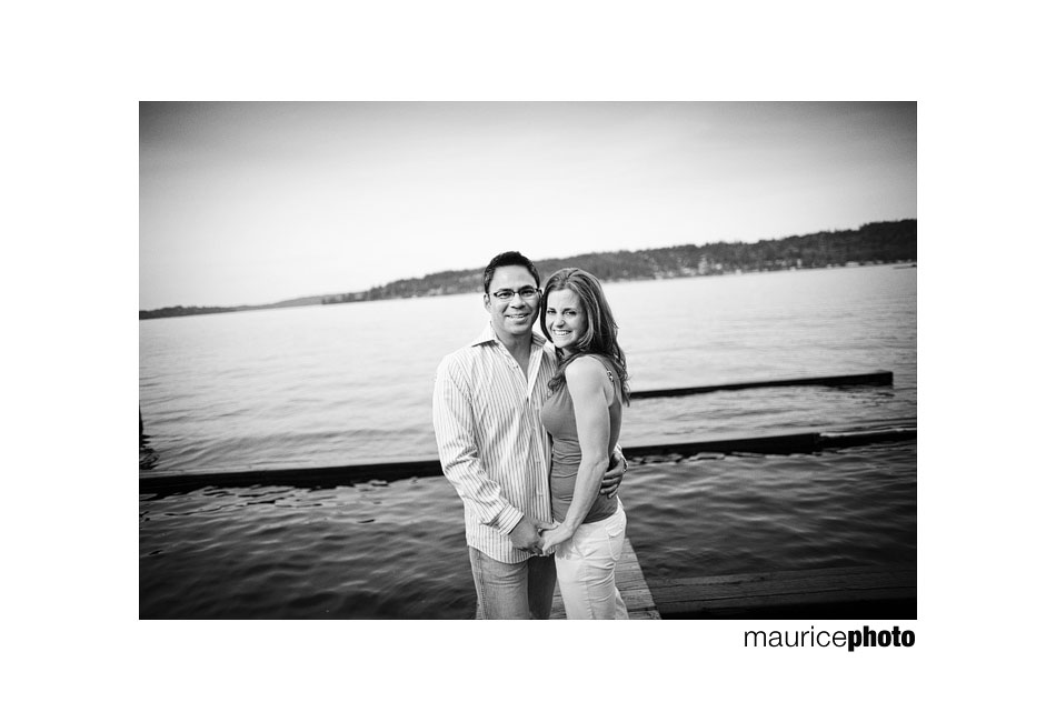 Picture of a couple posing on a dock near the lake. 
