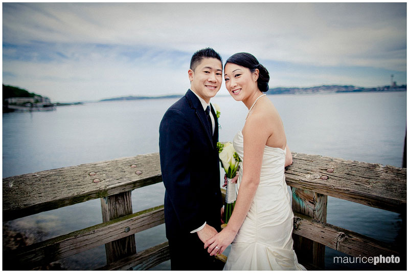 A bride and groom pose on the waterfront by Saltys